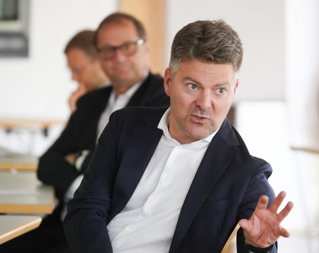 Auf dem Foto sieht man drei Männer am Tisch sitzen, im Vordergrund redet und gestikuliert ein Mann: Andreas Schwab (CDU) ist Berichterstatter des Europaparlaments zum Digital Markets Act