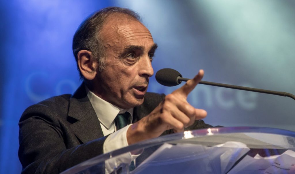 Porträtfoto von Eric Zemmour an einem Rednerpult, mittem im Gespräch