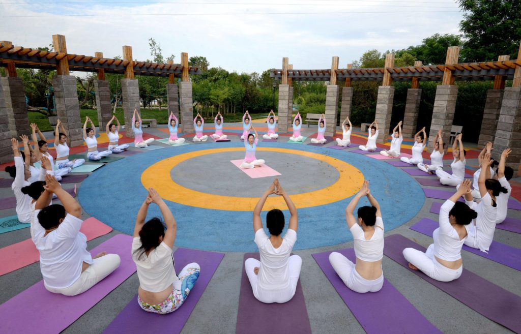 Yoginis sitzen im Kreis bei Atemübungen in einem Park