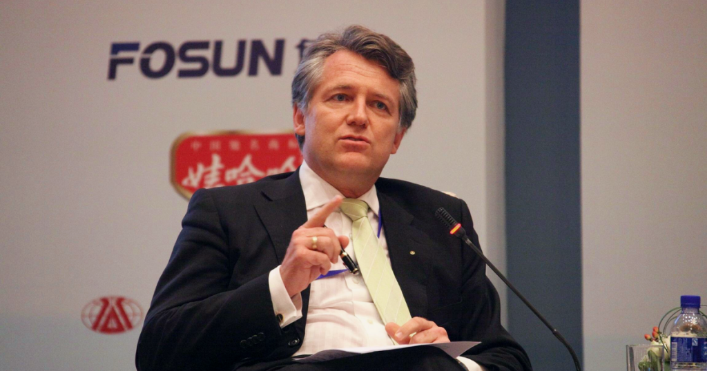 Foto von Jörg Wuttke, Präsident der EU-Handelskammer in China, er sitzt vor einem Mikrofon und hebt beim Sprechen einen Finger. 