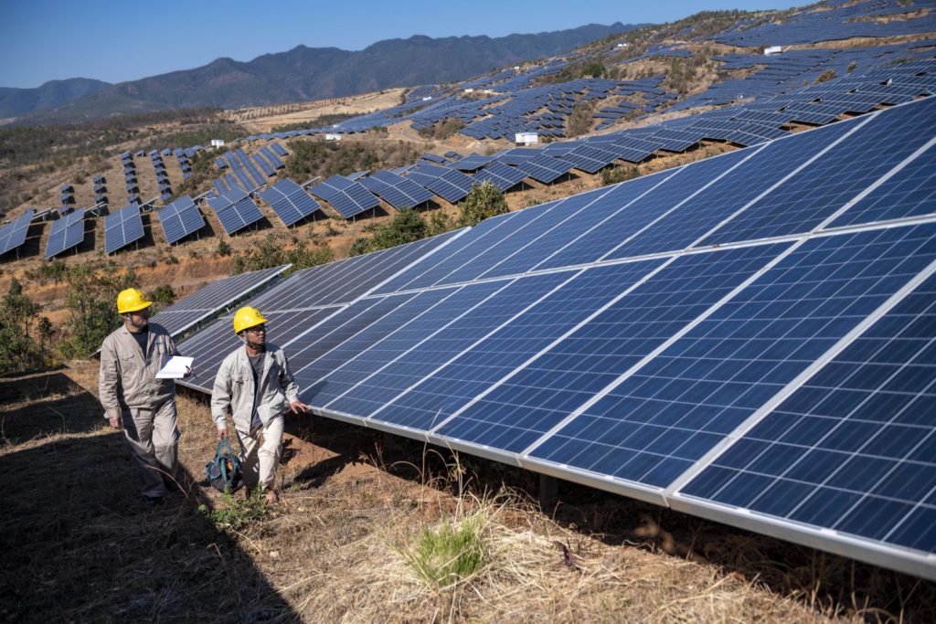 Zwei Ingenieure gehen einen Berg voller Solarzellen hinauf zur Inspektion - China möchte den Ökostrom-Sektor ausbauen.