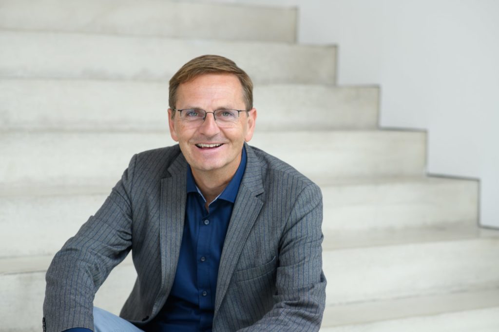 Man sieht Oliver Dickhäuser auf einer Treppe sitzend, er lehrt Pädagogische Psychologie an der Universität Mannheim: Er vertritt die Meinung, dass Noten ein guter Indikator für Erfolg im Studium sind.