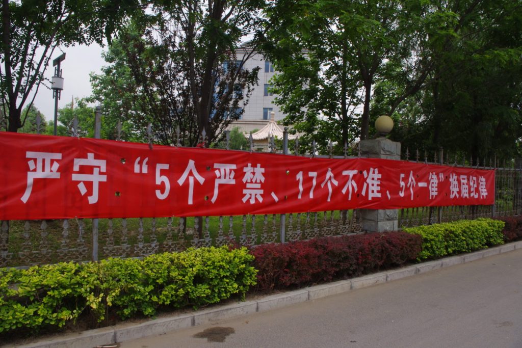Chinas Partei-Sprache: Sinnlose Zahlen-Parole: Slogan auf Banderole im Vorort von Peking während der politischen Wechselzeit (Aufnahme von 2013). Darauf steht: 