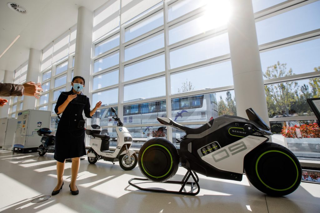 Eine Mitarbeiterin der Daxing International Hydrogen Energy Demonstration Zone in Beijing zeigt auf ein Wasserstoff-Hybrid-Motorrad