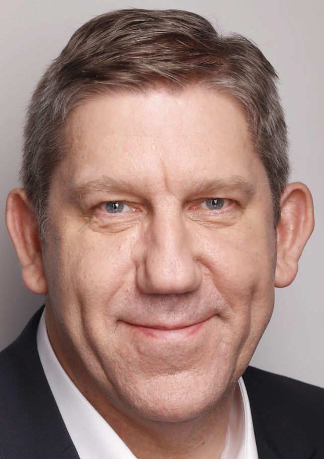 Porträtfoto von Andreas Schwarz, Berichterstatter der SPD für den Wehretat, im Anzug vor grauem Hintergrund. 