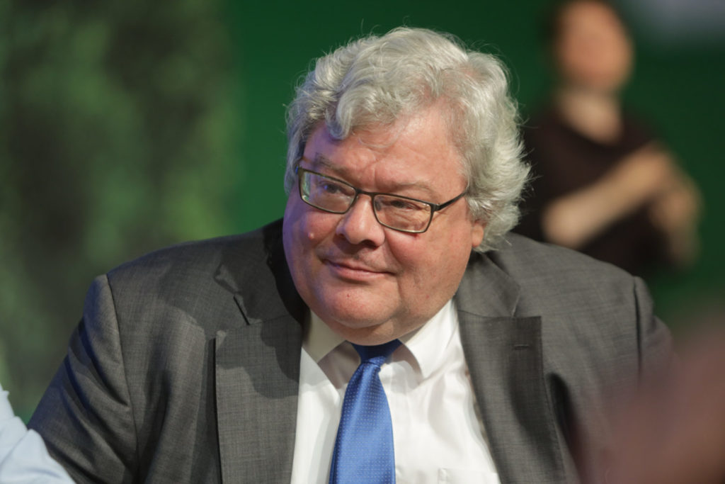 Porträtfoto von Reinhard Bütikofer im Anzug vor grünem Hintergrund, er gehört seit 2009 dem Europaparlament an. 