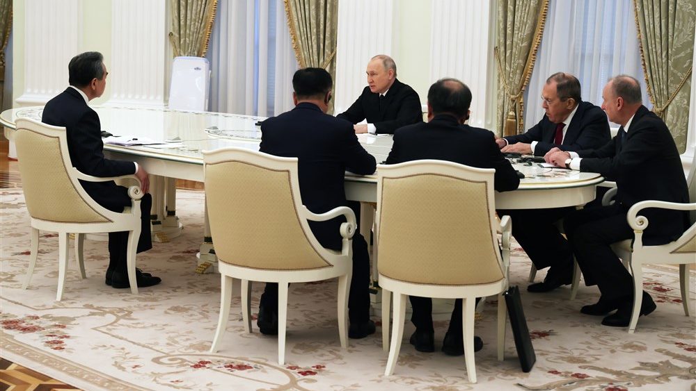 Putin und Wang Yi sitzen mit ihren Delegationen am Tisch im Kreml