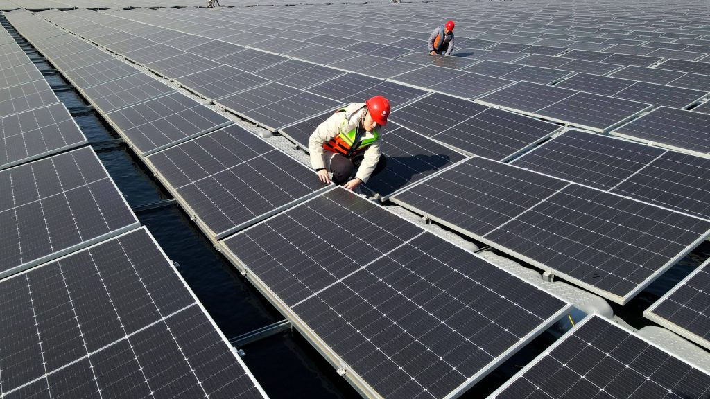 Zwei Installateure kontrollieren Module einer schwimmenden Solaranlage in China