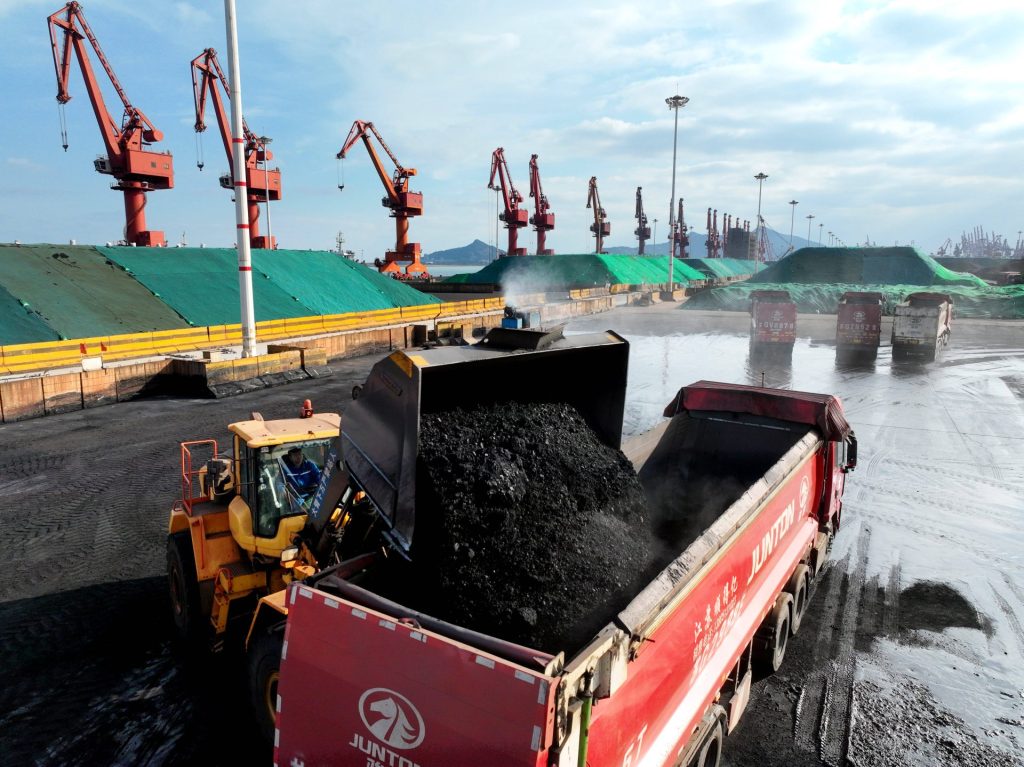 Ein Bagger kippt Kohle in einen bereit stehenden Laster an der Kaianlage im Hafen von Lianyungang.