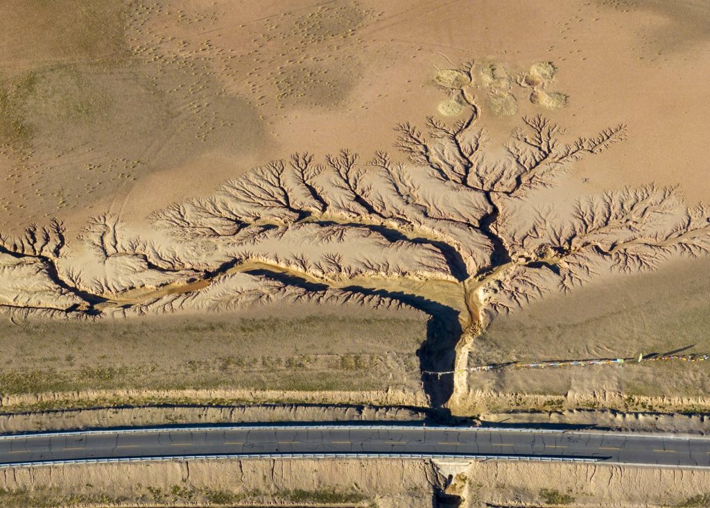 Landstraße und Wasserlauf in Nyima (Tibet) aus der Vogelperspektive