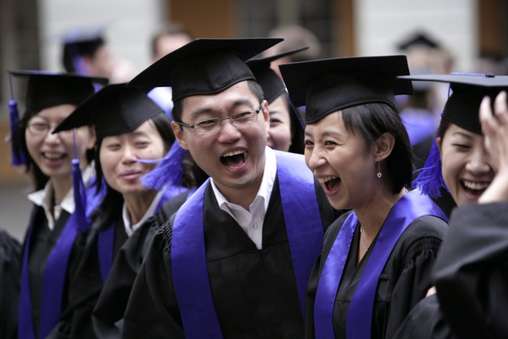 Studierende aus China in Talar und Barett bei einer Absolventenfeier.