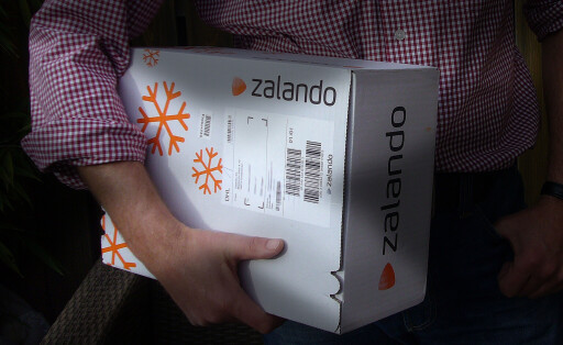 Ein Mann trägt ein Paket von Zalando unter seinem Arm.
