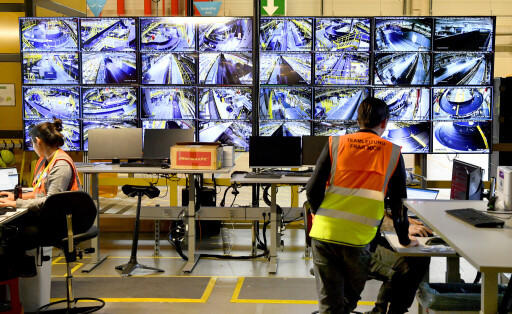 Eine Frau mit der Weste "Teamleitung" steht vor einer Reihe von Monitoren, die die Arbeit im Sortierzentrum von Amazon in Witten überwachen.