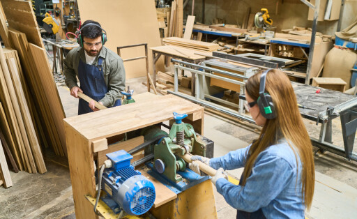 Ein junger Mann und eine Frau in einer Schreinerwerkstatt am arbeiten