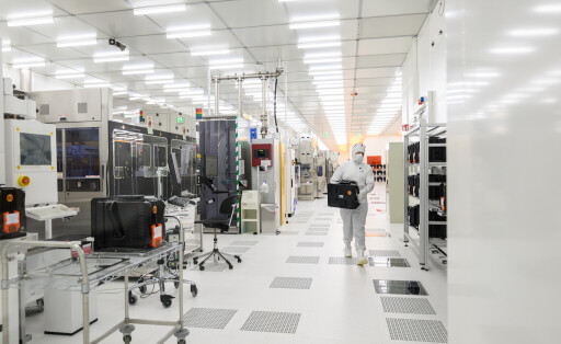 Ein Mitarbeiter geht im Fraunhofer-Institut für Photonische Mikrosysteme IPMS durch einen Reinraum zur Herstellung von 300-Millimeter-Wafern.