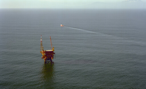 Offshore Oil Platform, Tasman Sea, New Zealand An offshore oil platform stands in the ocean with a ship sailing in the distance, leaving a wake behind it, Tasman Sea, New Zealand Tasman Sea New Zealand evpe00445 Copyright: xConnectxImagesx