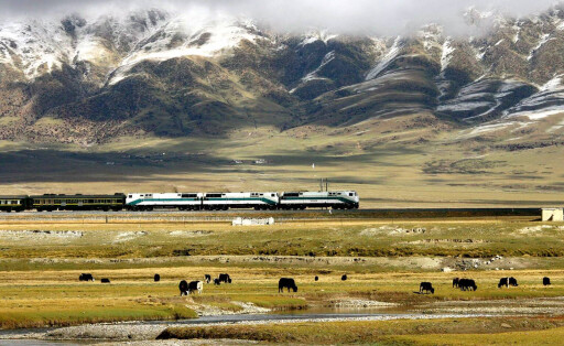 Zug der Lhasa-Eisenbahnlinie fährt vorbei an der Gebirgskette Nyainqentanglha in der chinesischen autonomen Region Tibet.