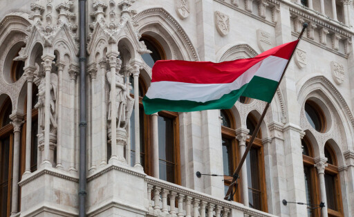 National hungarian flag waving on wind on the facade of parliament building in Budapest, Hungary