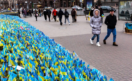 February 19, 2023, Kyiv, Ukraine: People walk by blue and yellow Ukrainian national flags with names of fallen soldiers