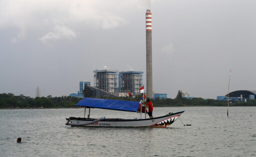 July 24, 2022, Labuan, Indonesia: Fishing boat leaning, with The Banten 2 Labuan Coal Power Plant in the background at C