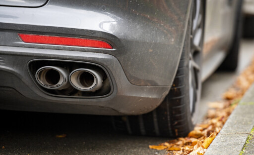 Abgas Verkehr, Auto, Umwelt: Blick auf eine Auspuffanlage eines Autos, das am Straßenrand neben dem Bürgersteig steht. G