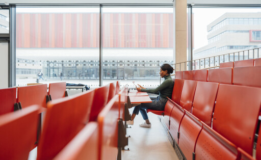 Young woman working on tablet PC sitting on seat in auditorium