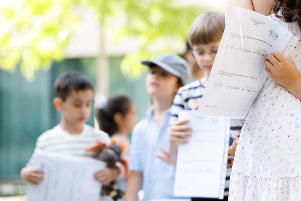 Kinder halten Schulzeugnis in der Hand.