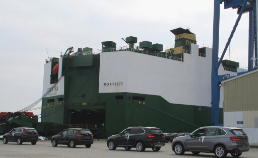 Autos der Marke BMWs warten bis sie in ein Autotransportschiff einfahren können.
