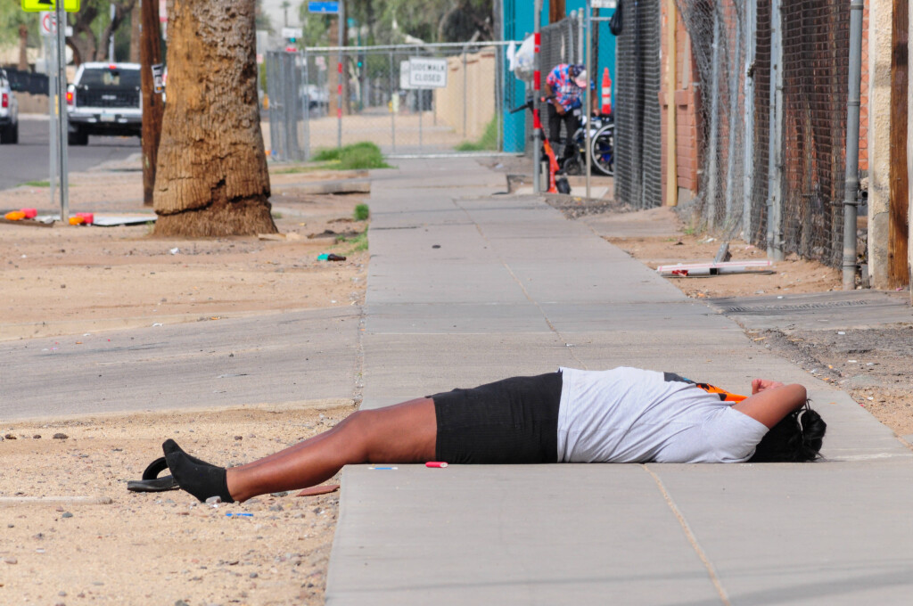 March 26, 2025, Phoenix, Arizona, USA: A woman lies on a sidewalk exposed to rising temperatures as summer approaches. The Phoenix Navigation Center, a new homeless shelter, aims to help unsheltered residents like her with dorm-style beds and private, air-conditioned rooms. It opens as triple-digit heat returns to the Valley, after 2024â€the hottest year on record in Phoenix, when 600 people died from heat-related causes, about half of them unhoused. Phoenix USA - ZUMAb270 20250326_znp_b270_018 Copyright: xEduardoxBarrazax