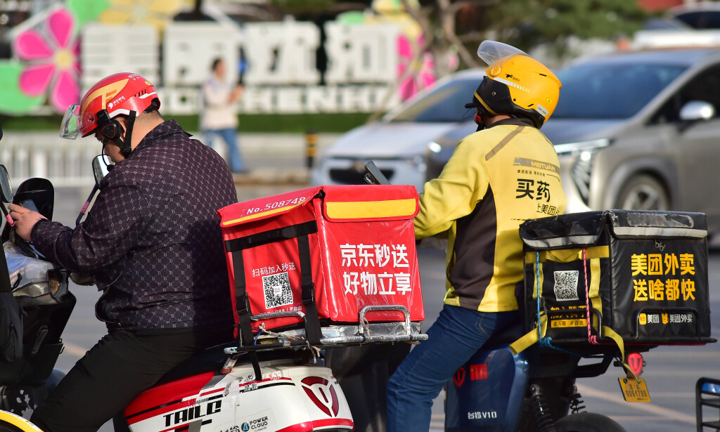 Food delivery riders of JD Takeaway (L), the food delivery service under China s e-commerce giant JD.com, and Meituan (R) wait for the green light on the road on April 23, 2025 in Shenyang, Liaoning Province