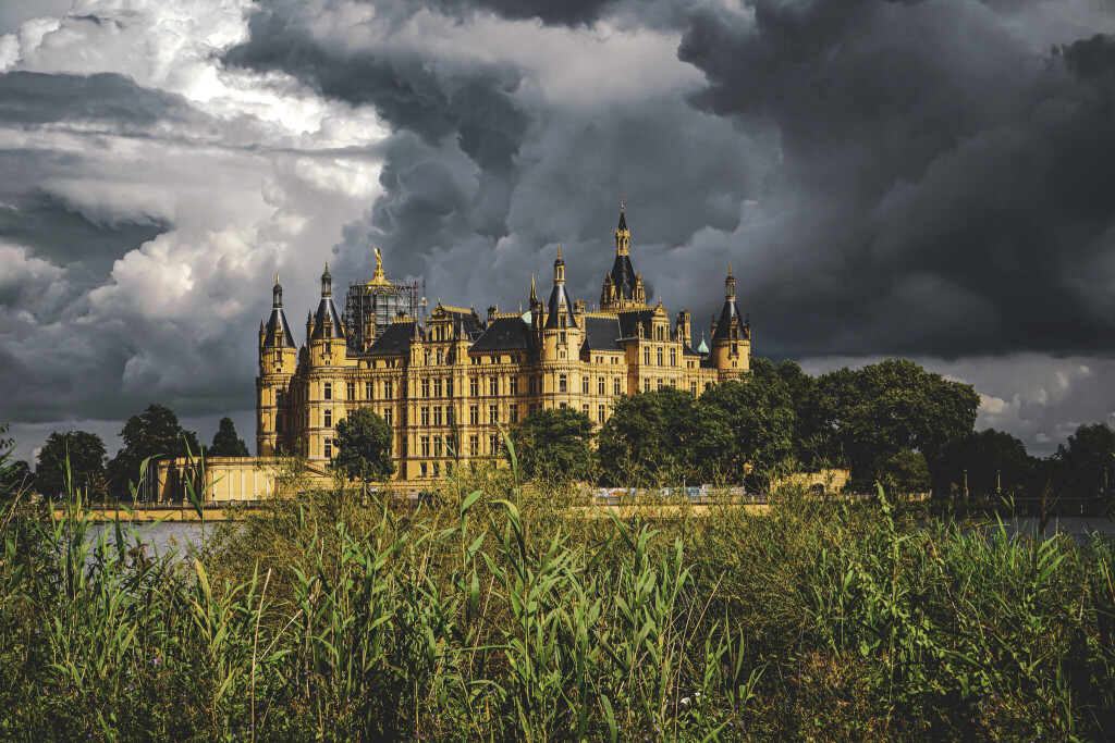 Hinter dem sandsteinfarbenen Schloss Schwerin ziehen dunkle Wolken am Himmel zusammen.
