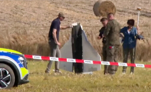 Sicherheitsleute heben die Überreste einer russischen Drohne auf einem Feld in Polen auf.