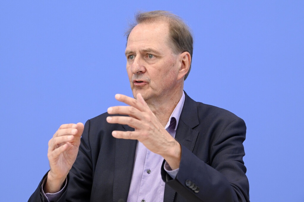 Dirk Messner trägt einen Anzug und ein fliederfarbenes Hemd. Er ist auf der Bundespressekonferenz, der Hintergrund ist im typischen Blau.
