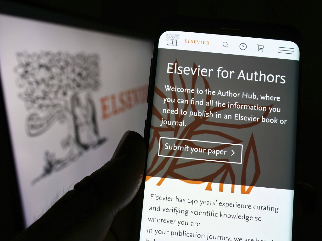 Person hält Smartphone mit Website des Wissenschaftsverlags Elsevier auf dem Bildschirm vor Logo.
