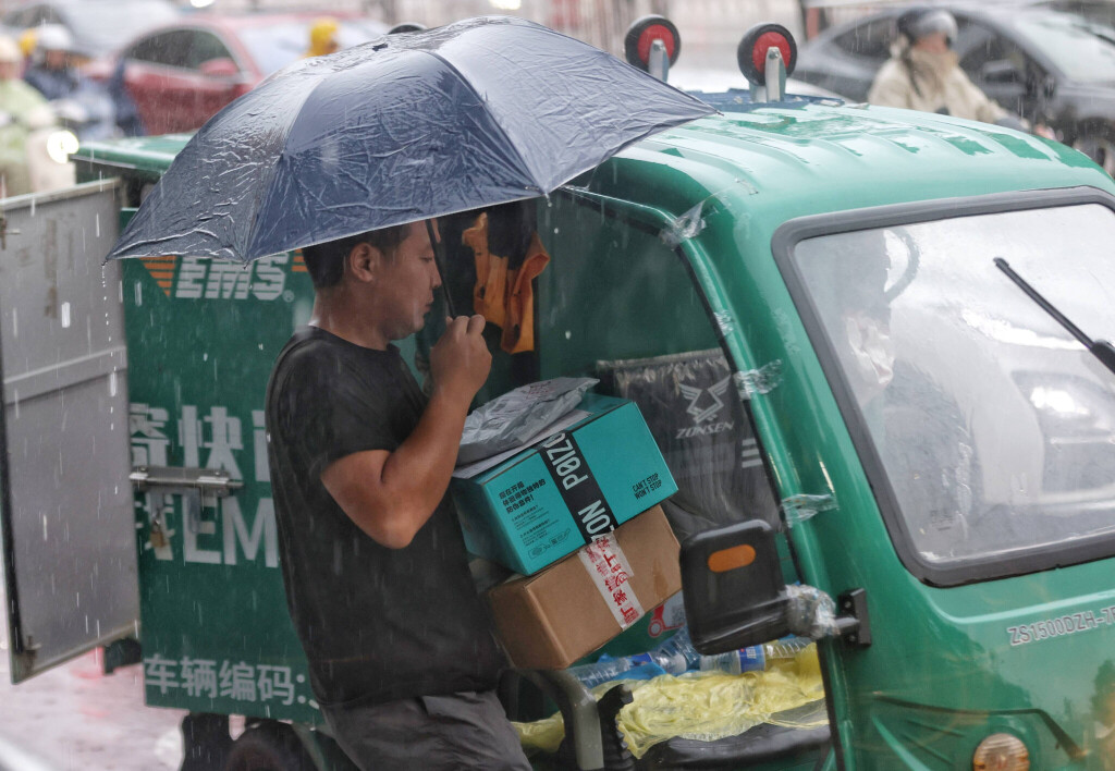 19.08.2025 Ein Paketlieferant liefert trotz Flutwarnung der Stufe 3 für Peking weiter aus.
