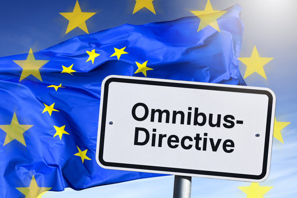 Omnibus-Directive steht auf einem Schild, im Hintergrund die EU-Flagge.
