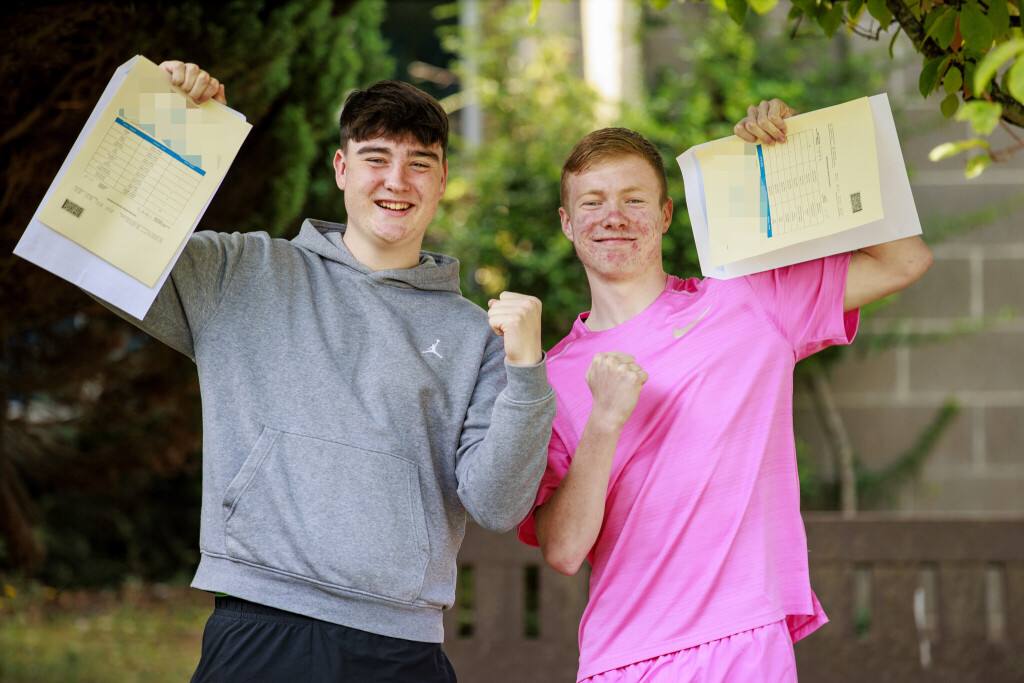 Zwei Schüler halten ihr Zeugnis hoch und freuen sich.