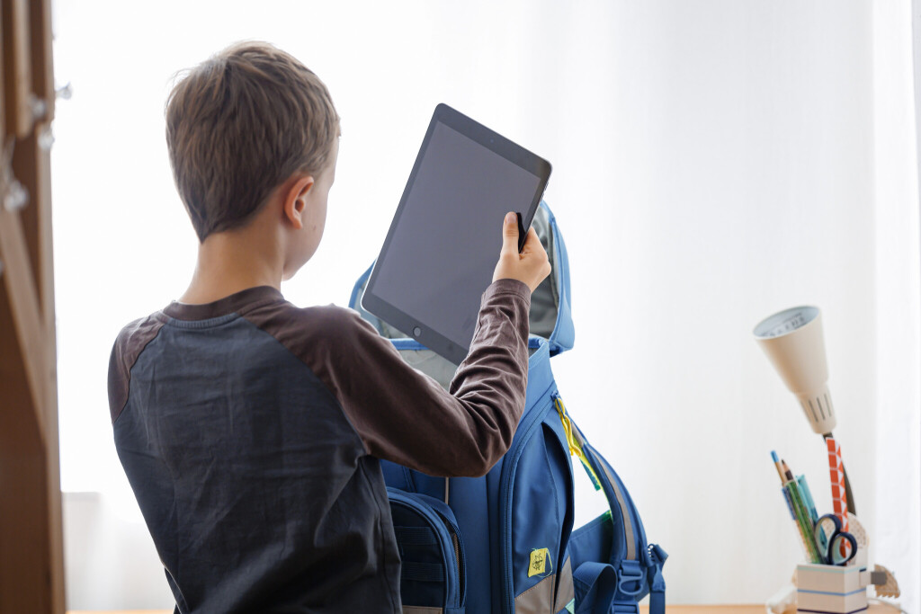 Ein Schüler packt ein Tablet in seinen Schulranzen.