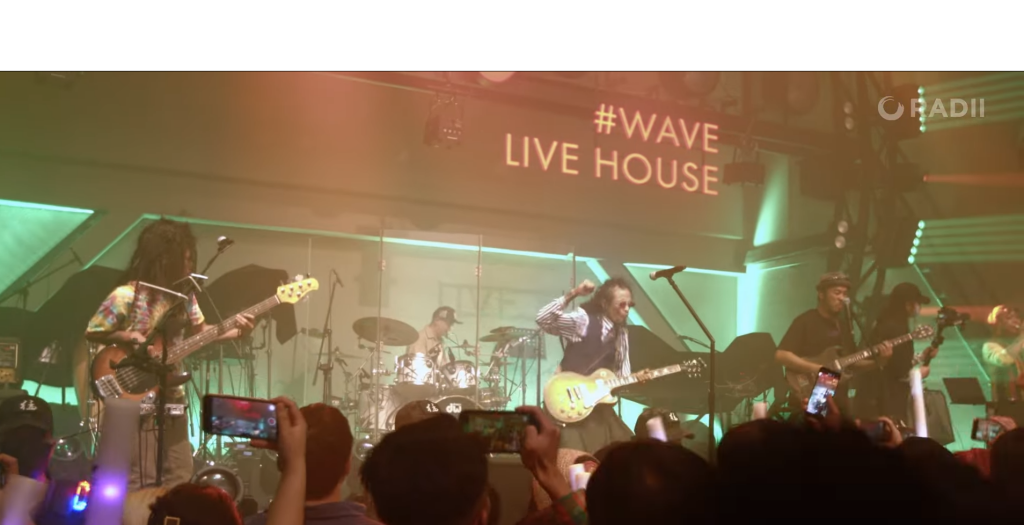 Eine Konzerthalle mit einer Band auf der Bühne.