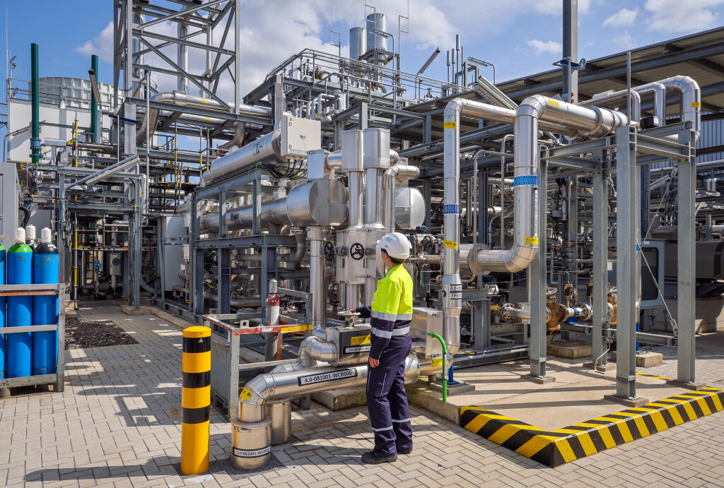 Oberhausen, Nordrhein-Westfalen, Deutschland - Gruener Wasserstoff bei Air Liquide, Wasserstoffproduktion im Chemiepark OQ Chemicals. TRAILBLAZER, ein 20 MW-Elektrolyseur zur Herstellung von gruenem, klimaneutralem Wasserstoff. Eine Ingenieurin steht an der Anlage, regelt an einem Schieberventil den Leitungsdurchfluss.
