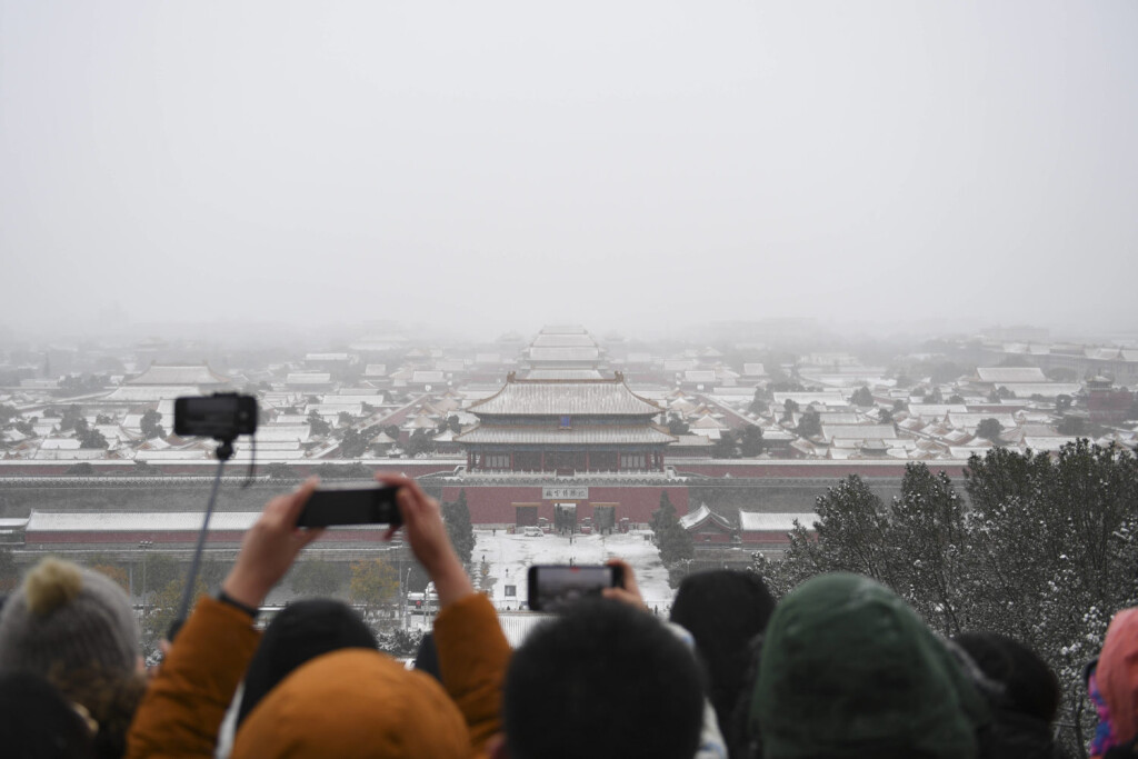 BEIJING, CHINA - NOVEMBER 07: People take photos of the snow-covered Palace Museum from Jingshan Park on November 7, 202