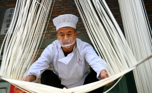220817 -- LUONAN, Aug. 17, 2022 -- Li Nianping, son of Li Changman, dries hollow noodles in Meidi Village of Bao an Township in Luonan County of Shangluo City, northwest China s Shaanxi Province, Aug. 16, 2022. Li Changman, a 66 years old villager of Meidi Village, has learned the unique hollow noodle making skills since he was a teenager. He is the inheritor of Luonan handmade hallow noodle making skills which is listed as a provincial intangible cultural heritage. He encouraged his child to learn this skill, and also taught the skills to villagers to increase their income. CHINA-SHAANXI-HOLLOW NOODLE CN TaoxMing PUBLICATIONxNOTxINxCHN