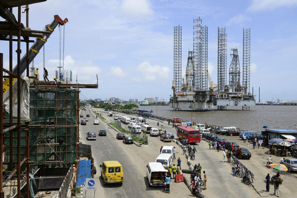 Nigeria Lagos, chinese CCECC Metro train construction and oil platform in Lagos port NIGERIA, City Lagos, two oil platform laying in Lagos port, Oritsetimeyin and Onome, and left flyover construction for new metro train by chinese company CHINA CIVIL CCECC, road traffic with VW minibus Lagos Lagos Nigeria