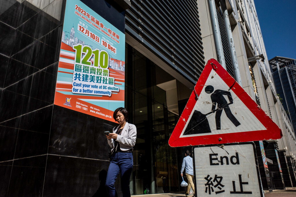 Werbung für die Hongkonger Bezirksratswahlen in China - 22. November 2023 Eine Frau geht an der Werbung für die Hongkonger Bezirksratswahlen vorbei, die auf der Straße in Hongkong hängt.